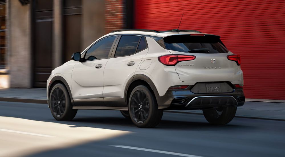 Rear view of a white 2026 Buick Encore GX driving on a paved road.
