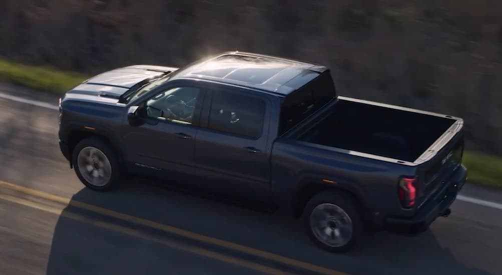 A black 2027 GMC Sierra 1500 driving on a highway.