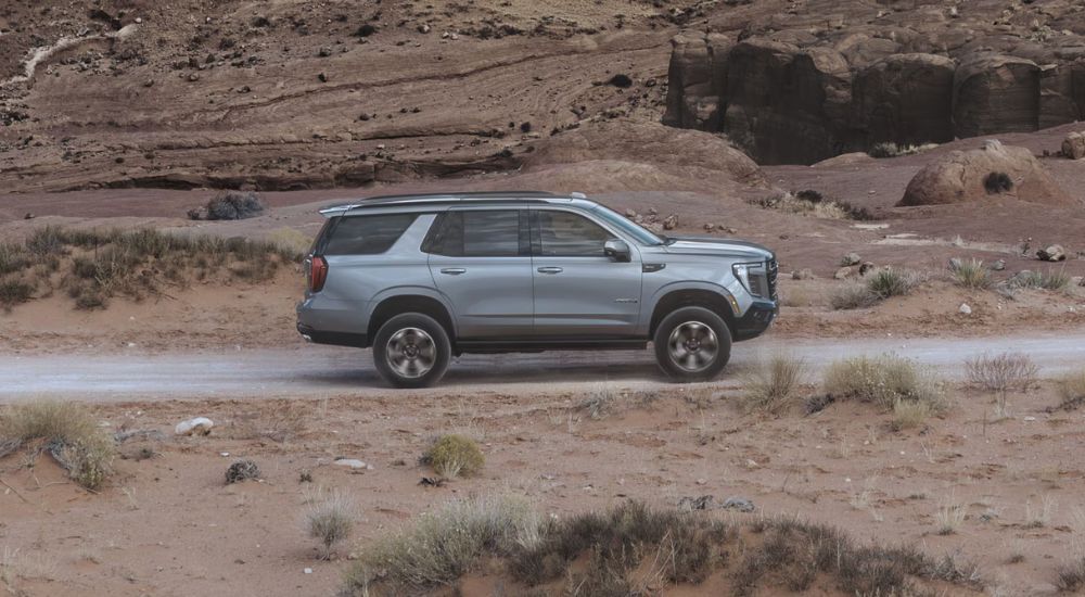 Grey 2027 GMC Yukon AT4 driving off-road.