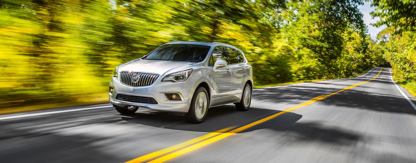 White 2017 Buick Envision driving down a road.