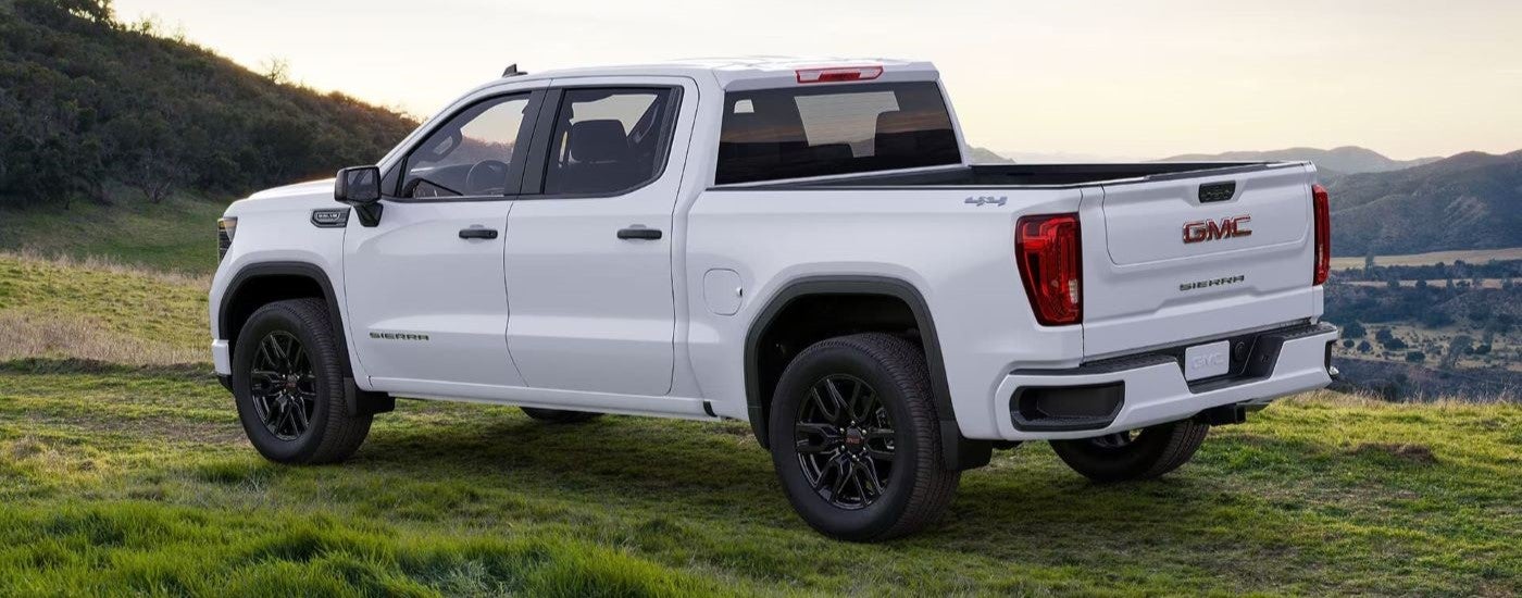 White 2024 GMC Sierra 1500 from the side in a grassy field.