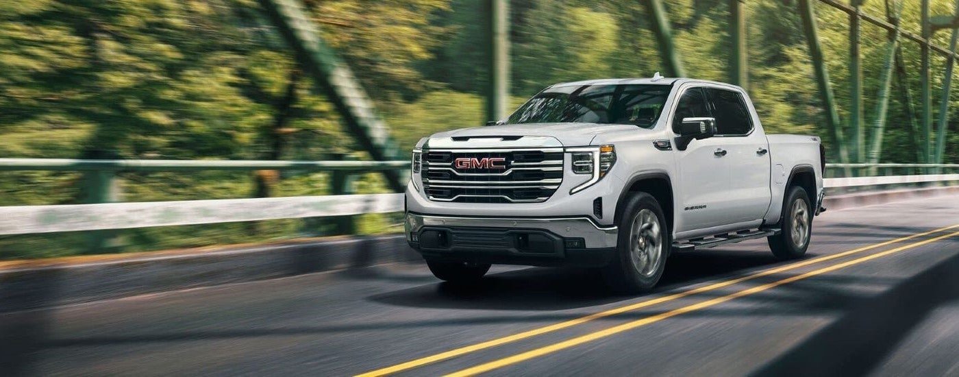 White 2026 GMC Sierra 1500 SLE driving across a bridge.