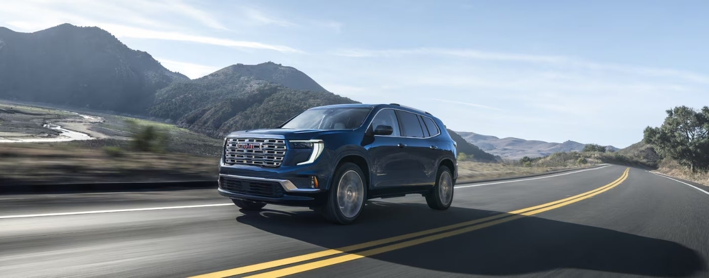 Blue 2026 GMC Acadia Denali on an open road