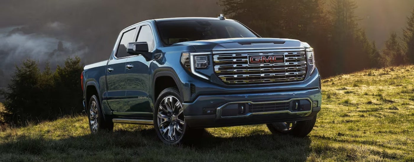 Blue 2026 GMC Sierra 1500 Denali driving down a road.