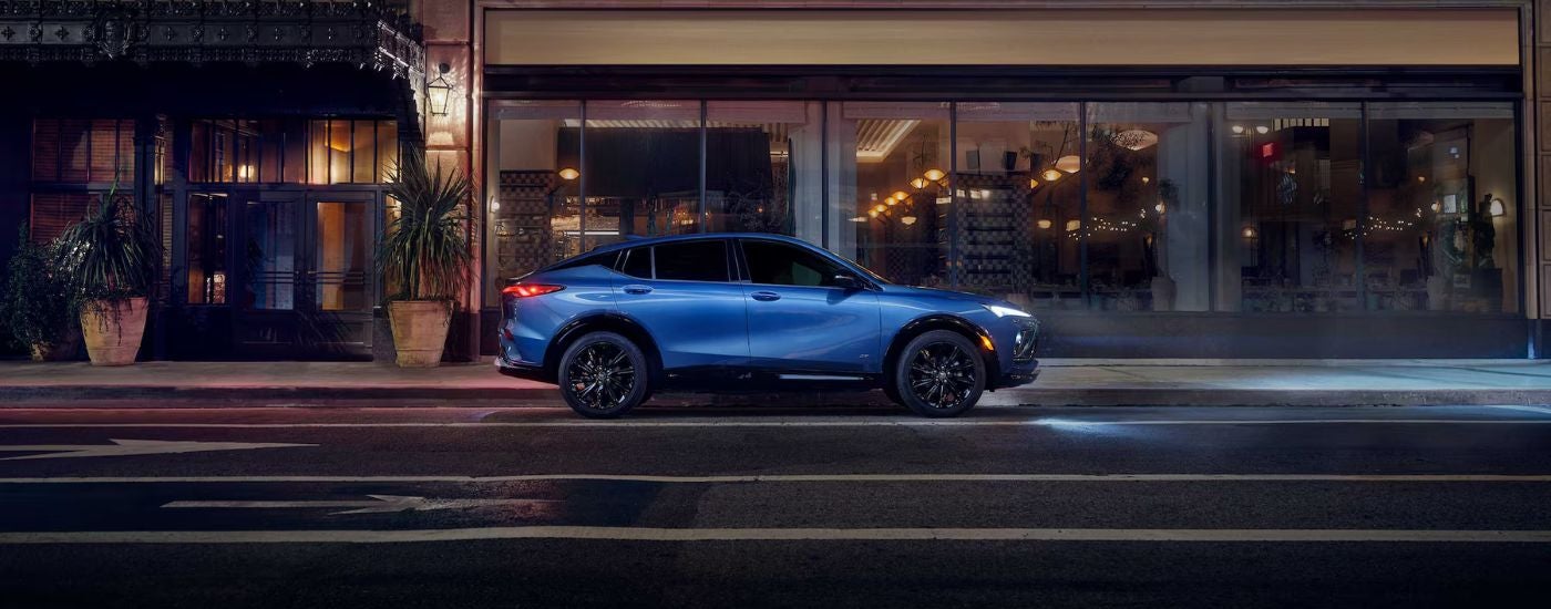 Blue 2026 Buick Envista driving on a city street at night.