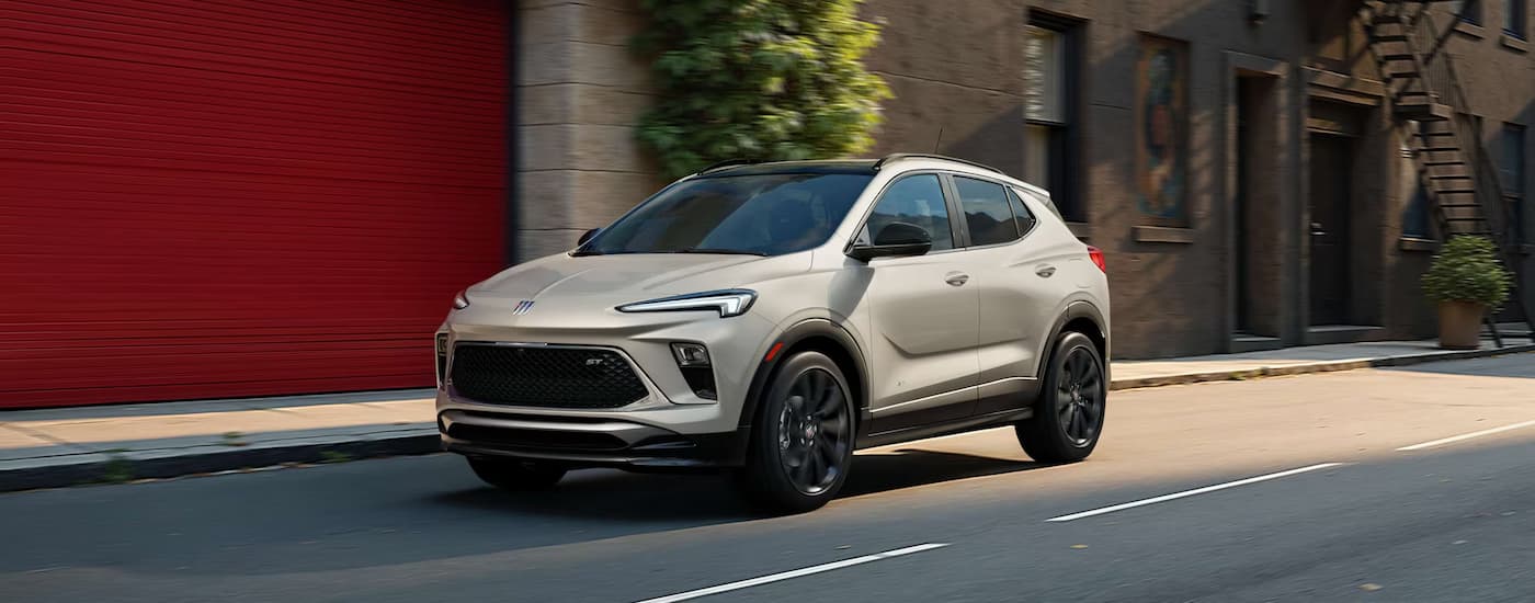Tan 2026 Buick Encore GX driving down a road.