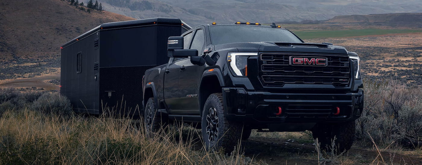 Black 2026 GMC Sierra 2500 HD towing a camper off-road.