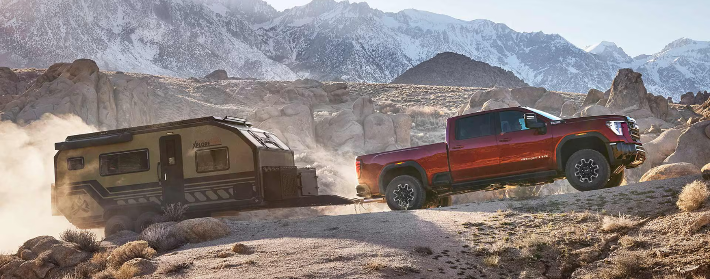 Red 2026 GMC Sierra 2500 HD towing a camper off-road