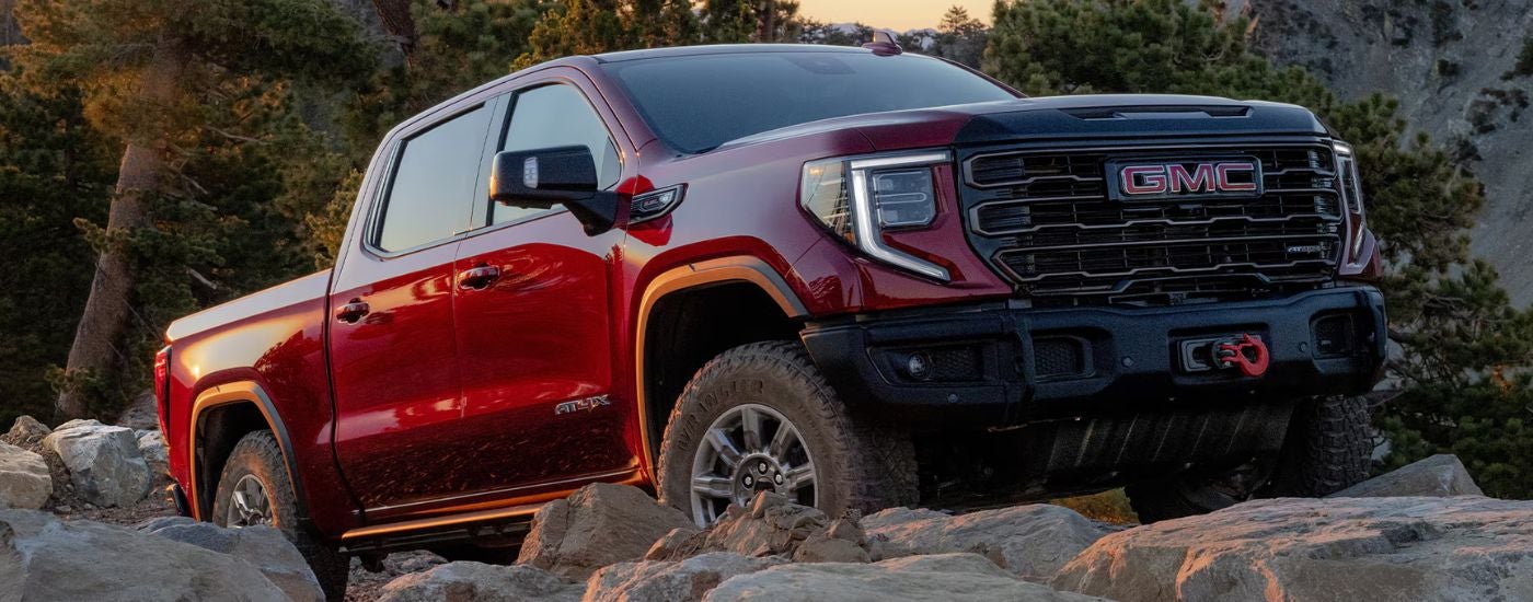 Red 2026 GMC Sierra 1500 driving on rough terrain.