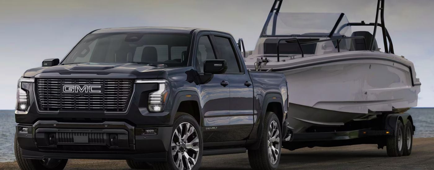 Black 2027 GMC Sierra 1500 Denali towing a boat.