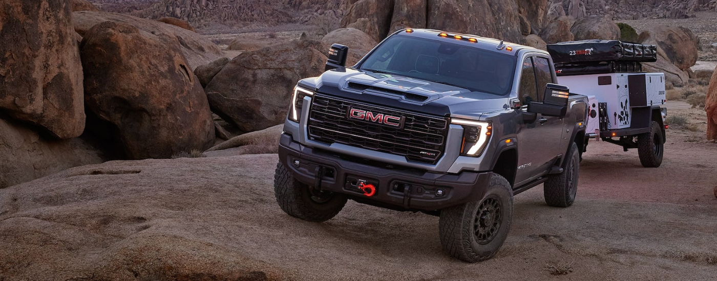 Grey 2027 GMC Sierra 2500 HD parked off-road with a camping trailer