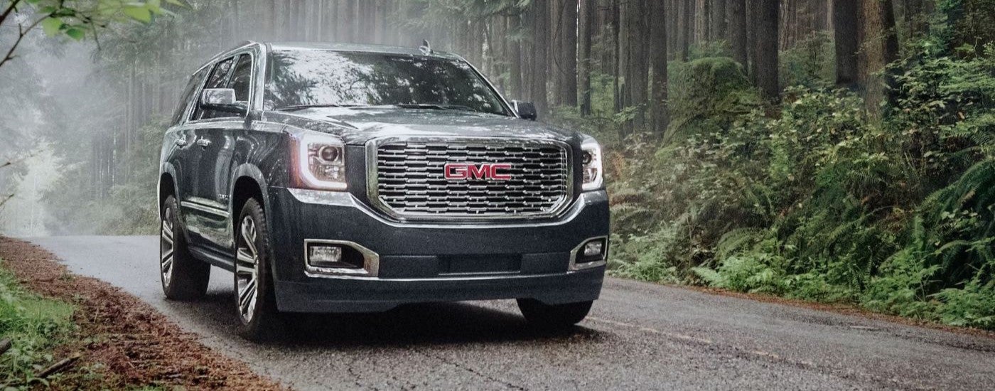 A gray 2020 GMC Yukon Denali driving in the rain.