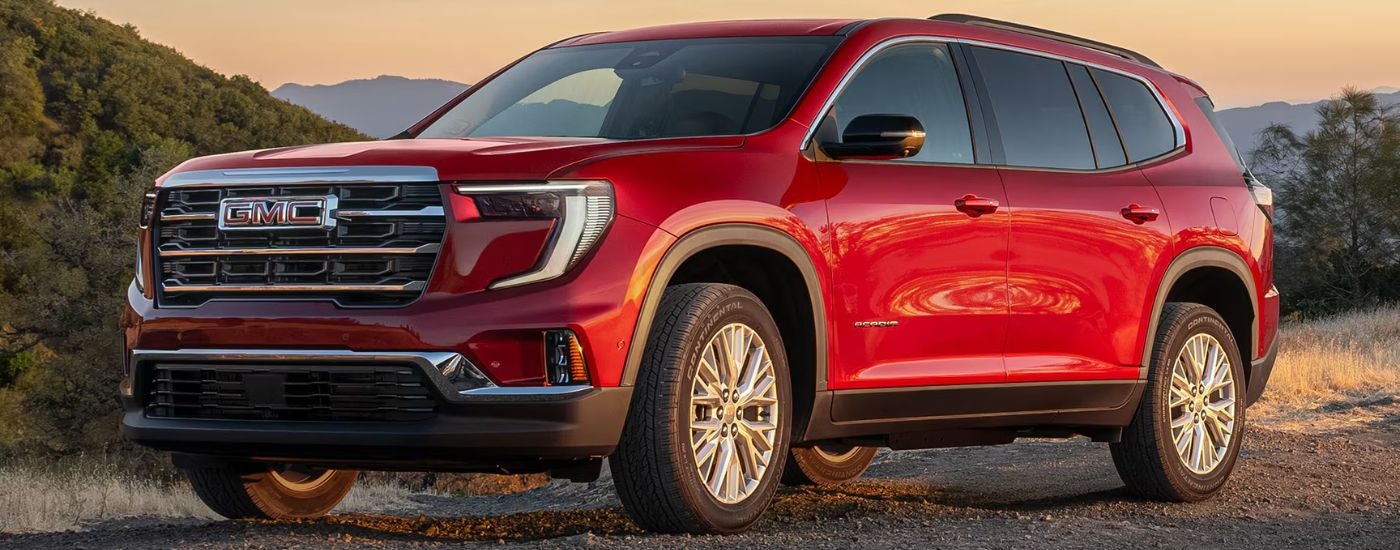 A red 2027 GMC Acadia parked off road at sunset.