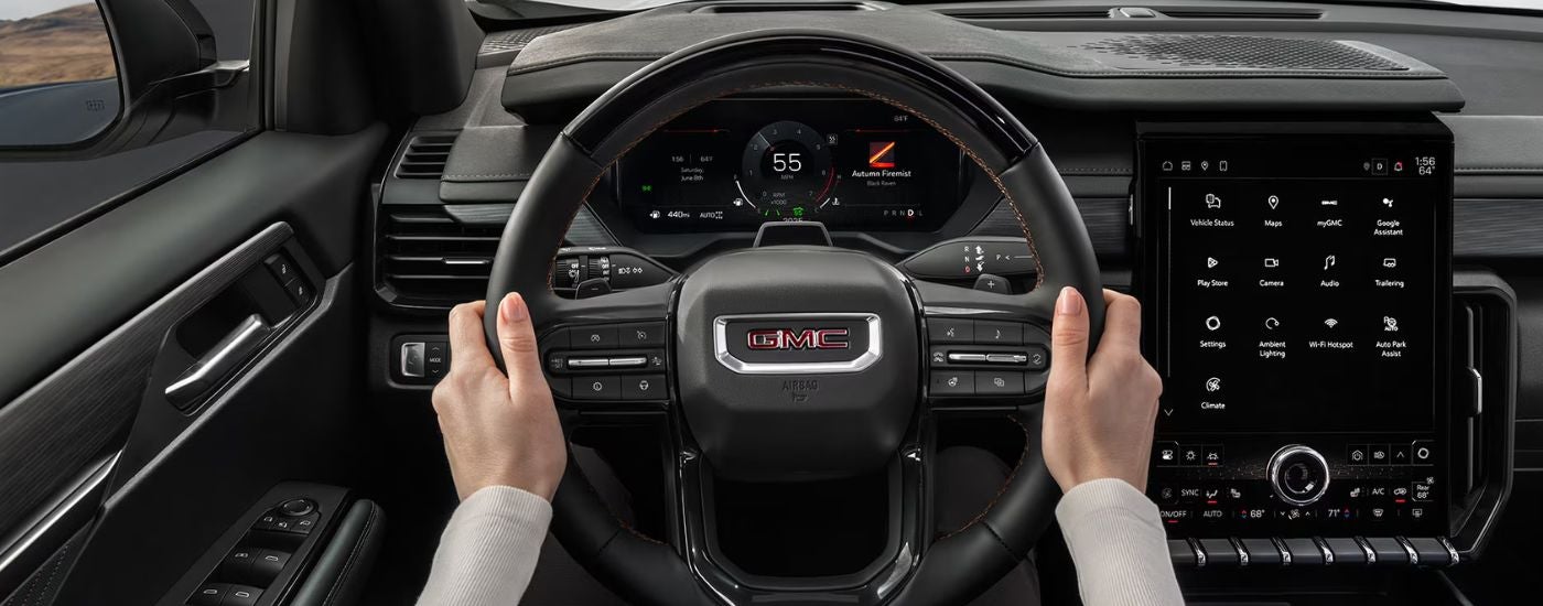Driver perspective inside a 2027 GMC Acadia with black leather details.