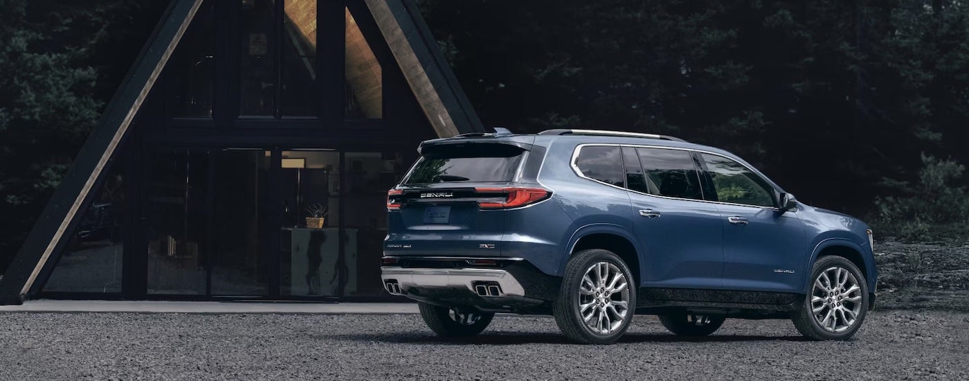 A blue 2026 GMC Acadia from the rear at an angle.