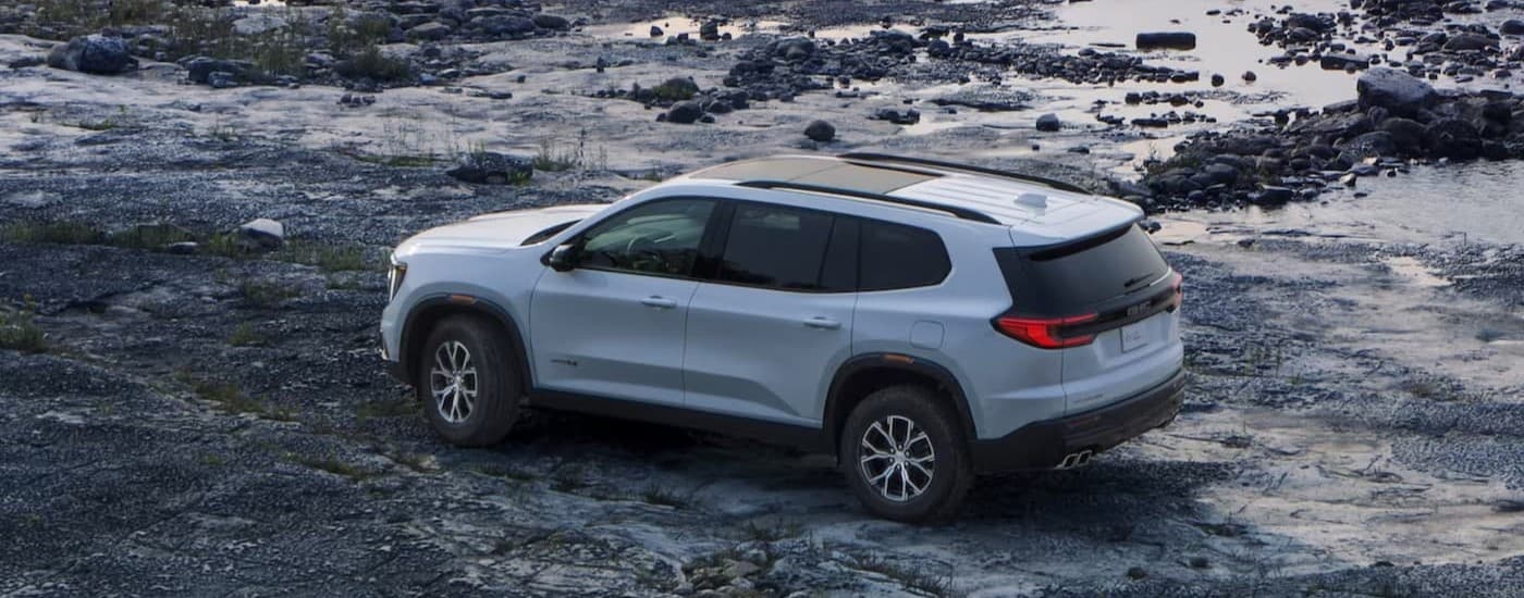 A white 2024 GMC Acadia AT4 parked off-road.