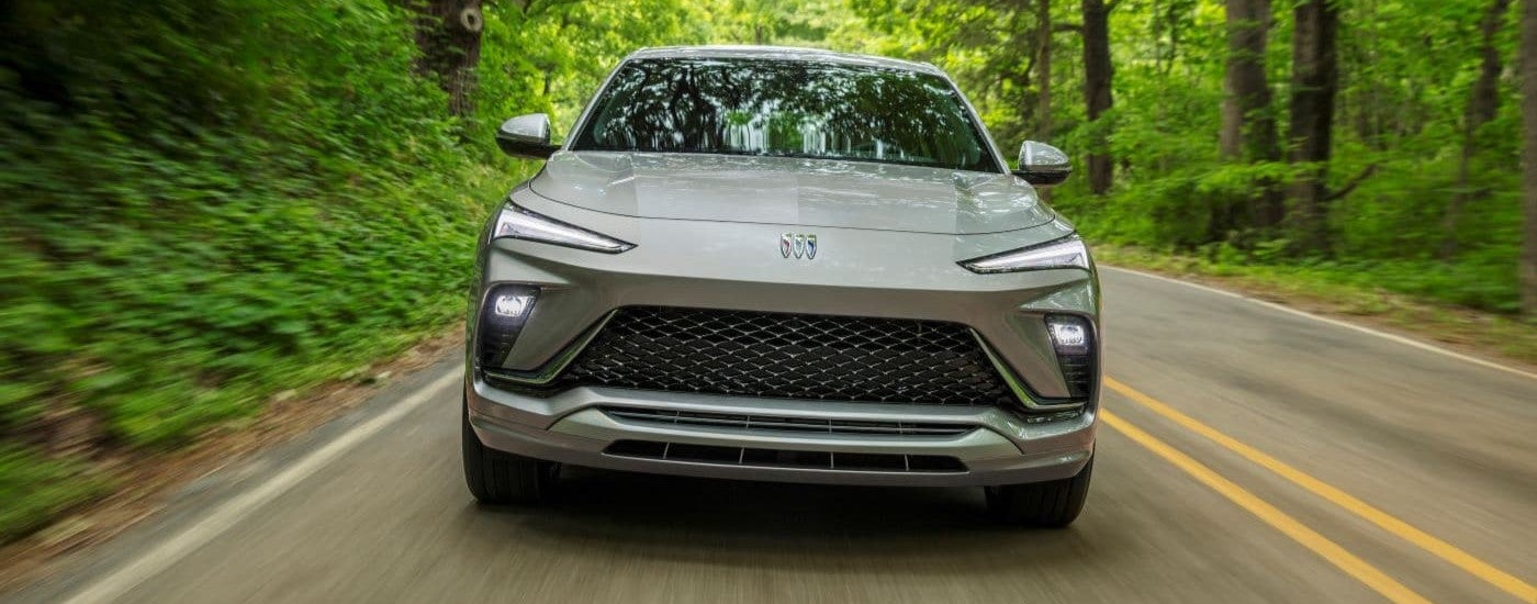 Grey 2024 Buick Envista Avenir driving on tree-lined road